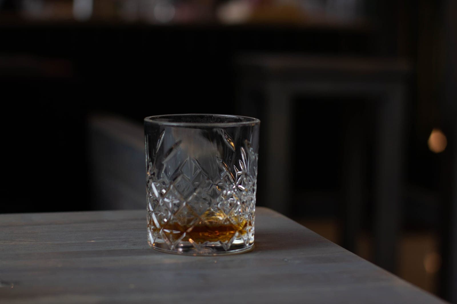 A rocks glass with whiskey on a bright table in daylight