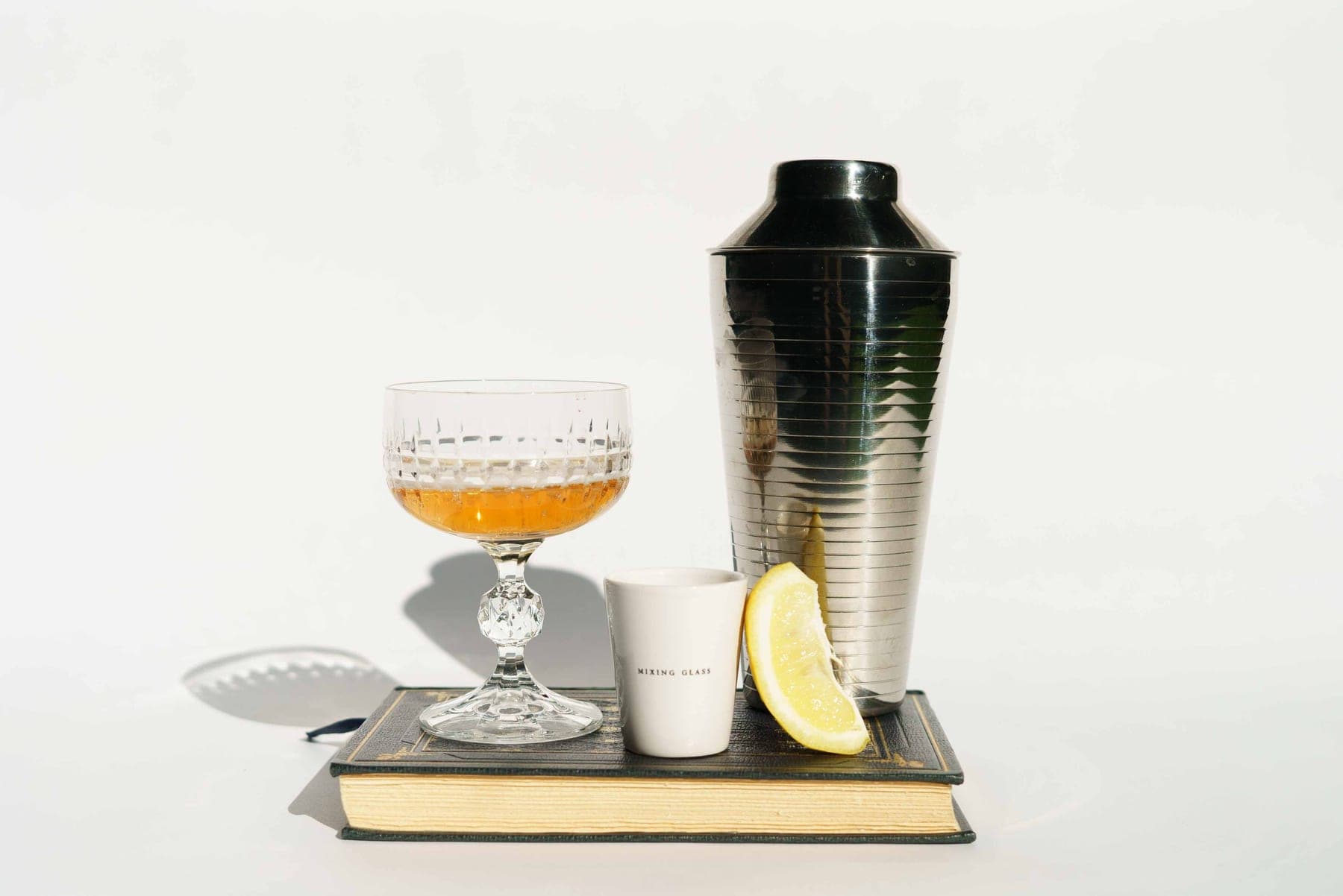 A cocktail shaker and a coupe glass on a bright white background