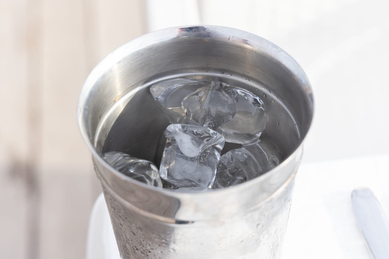 A stainless steel ice bucket filled with ice cubes